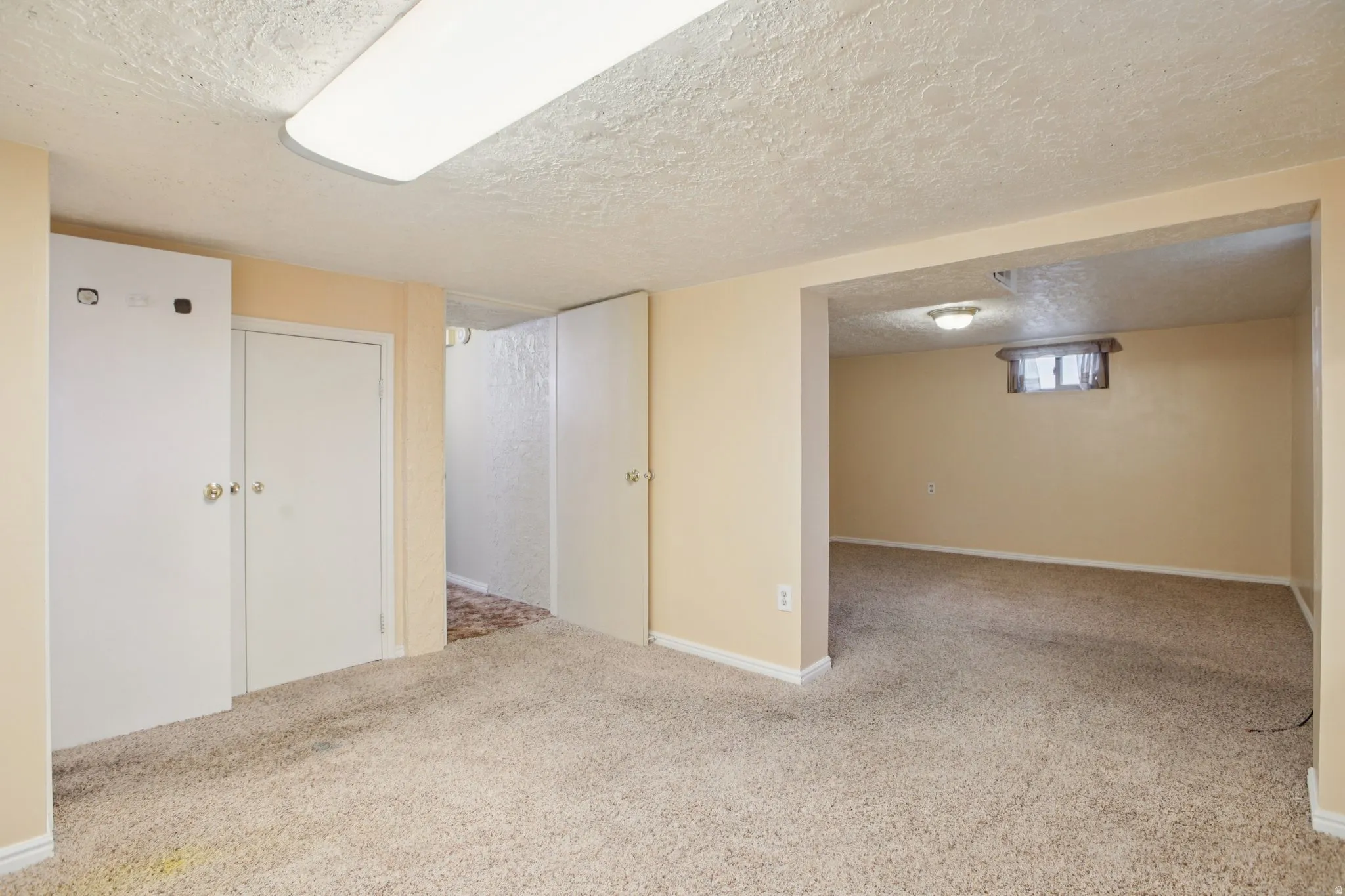 Basement with a textured ceiling and light carpet