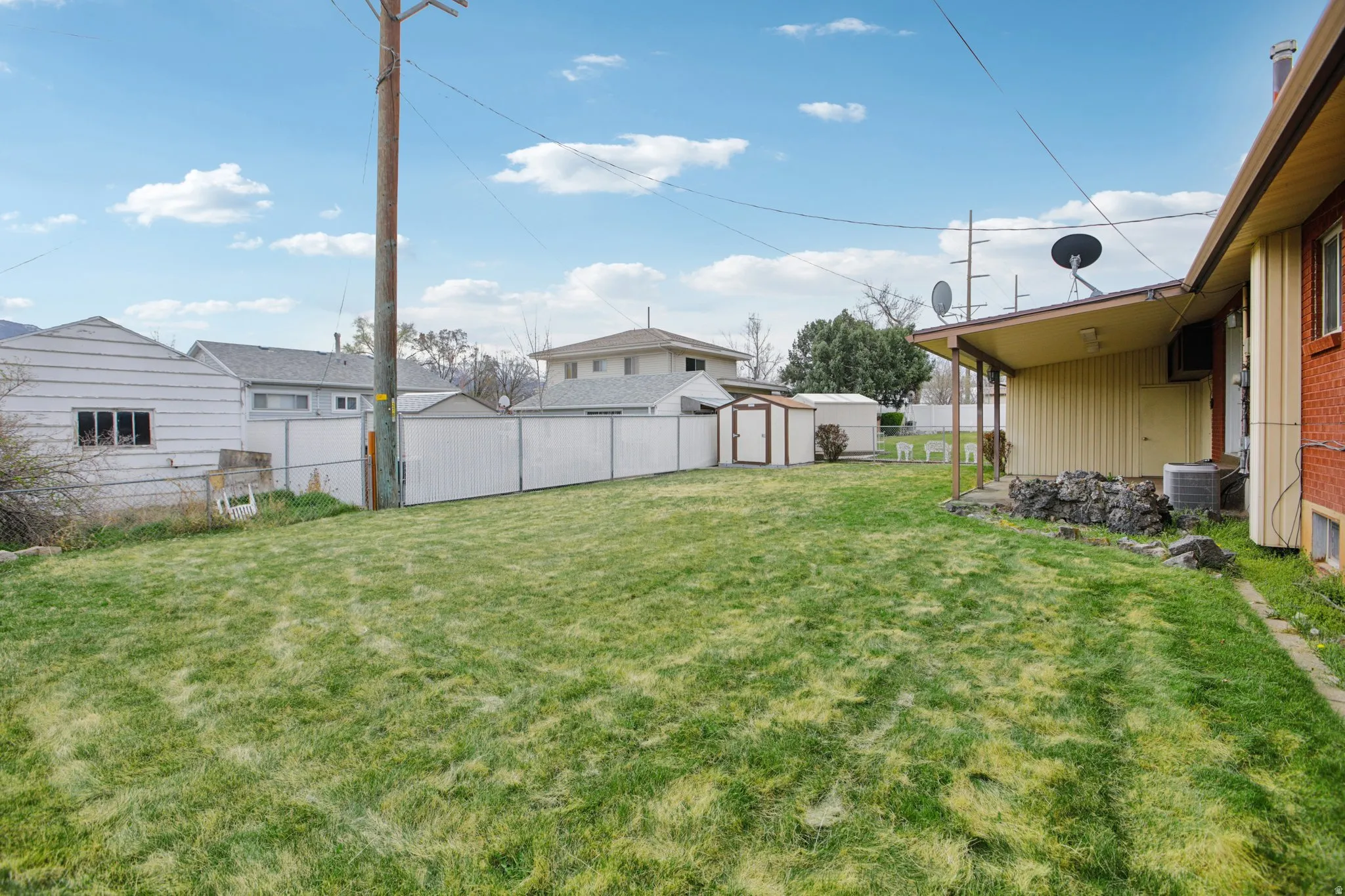 Fenced backyard featuring a storage shed