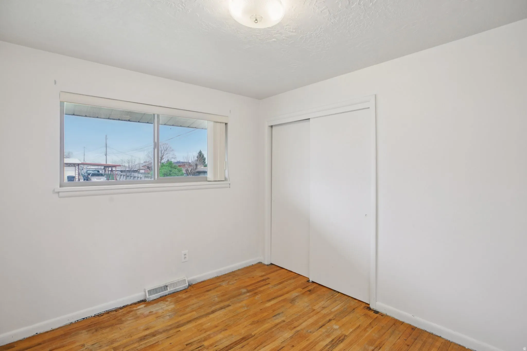 Unfurnished bedroom featuring light wood-type flooring, a closet, and a textured ceiling