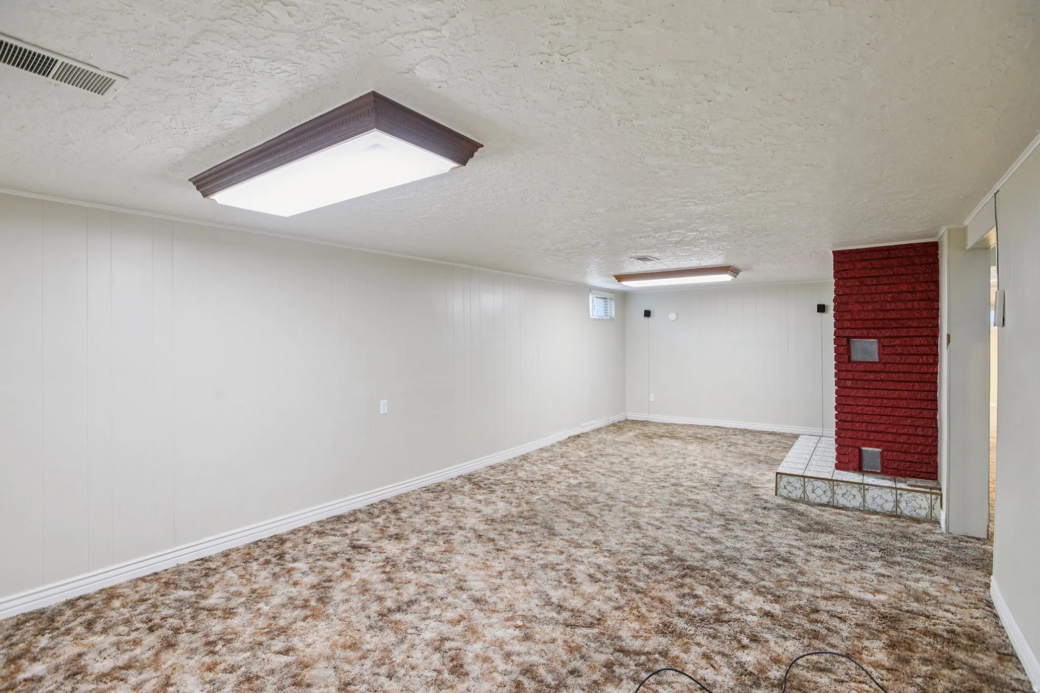 Finished below grade area with a textured ceiling and carpet floors