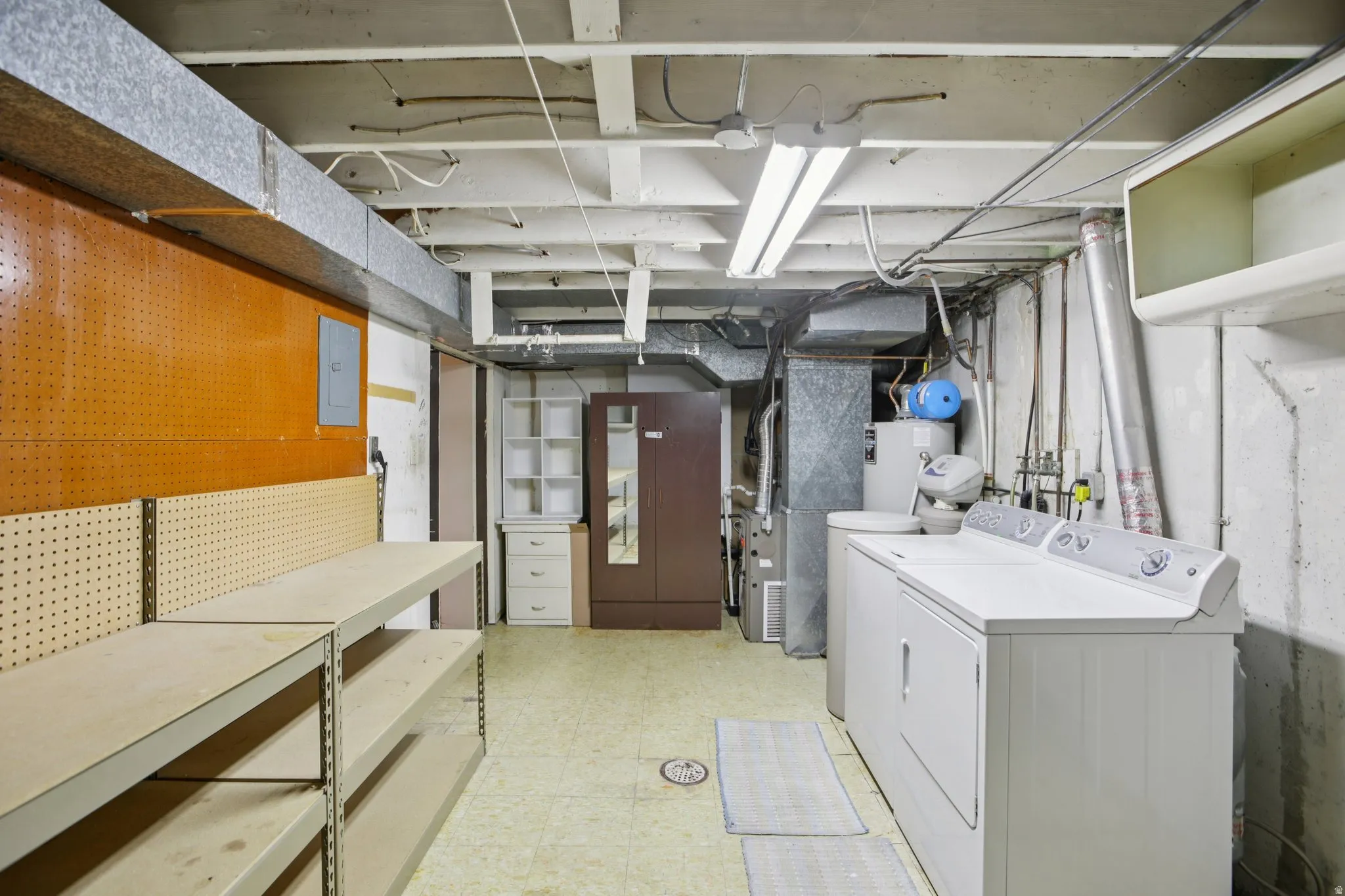 Unfinished below grade area with light floors, heating unit, washing machine and dryer, and water heater