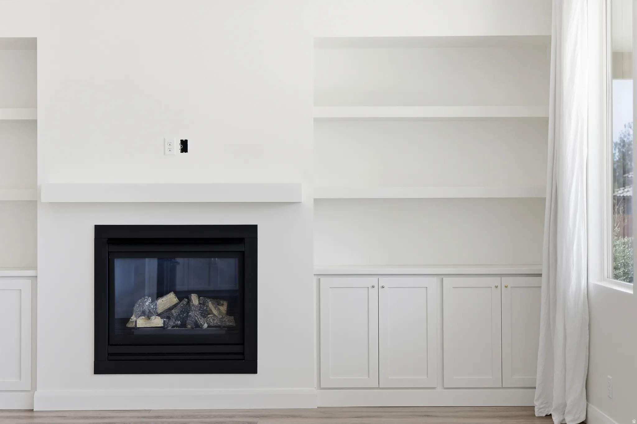 Detailed view of built in features, a glass covered fireplace, and wood finished floors