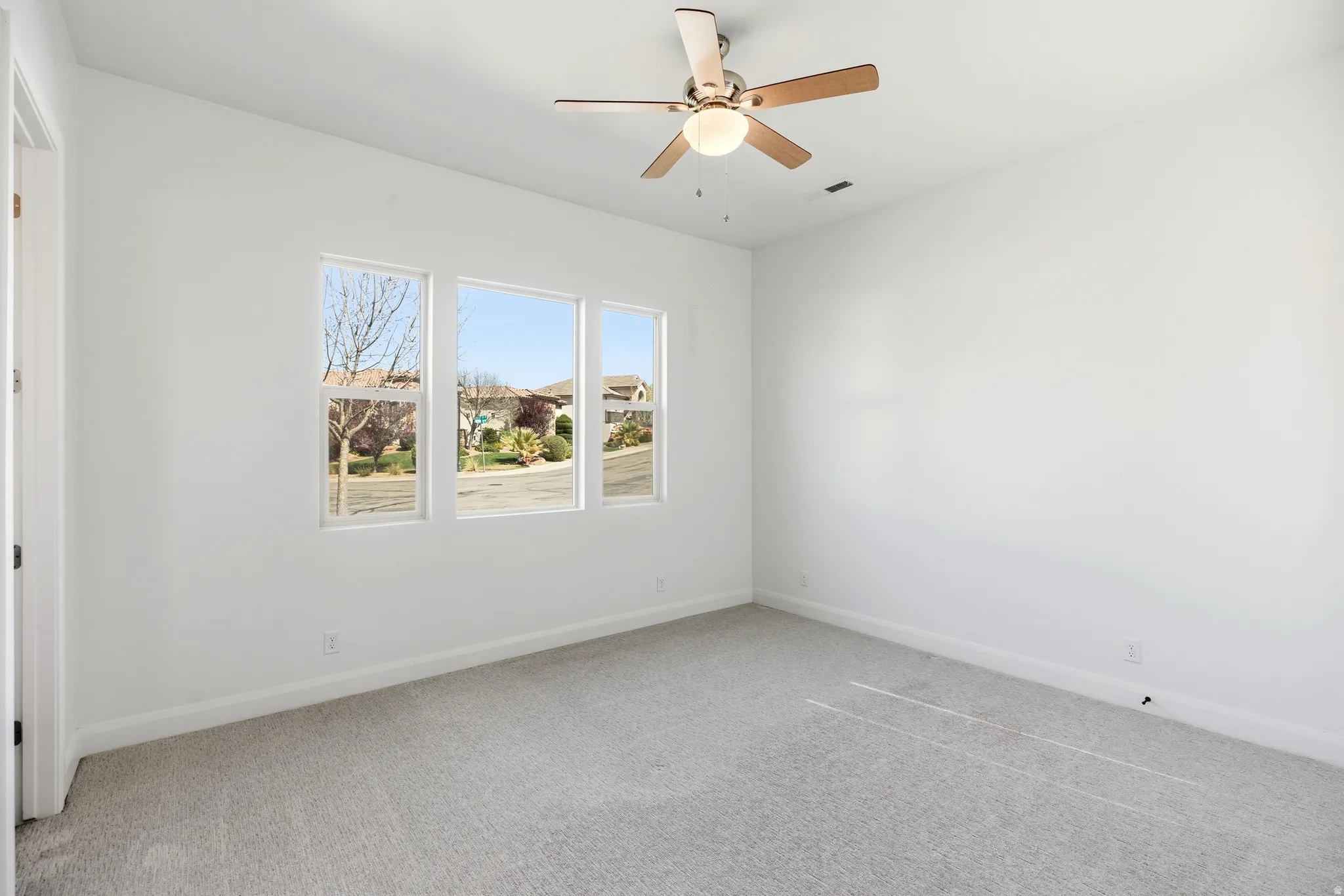 Spare room featuring light colored carpet and ceiling fan