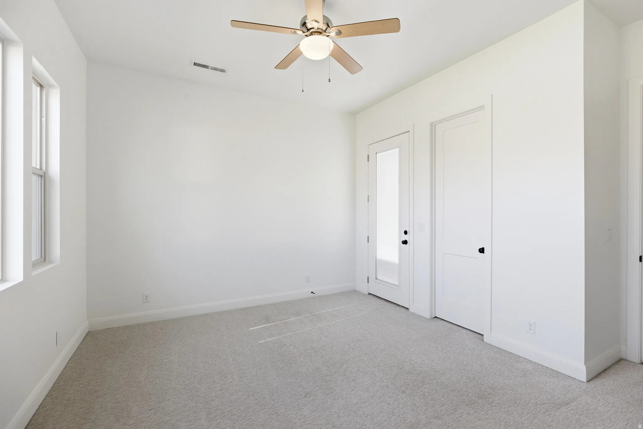Unfurnished bedroom with light carpet and ceiling fan