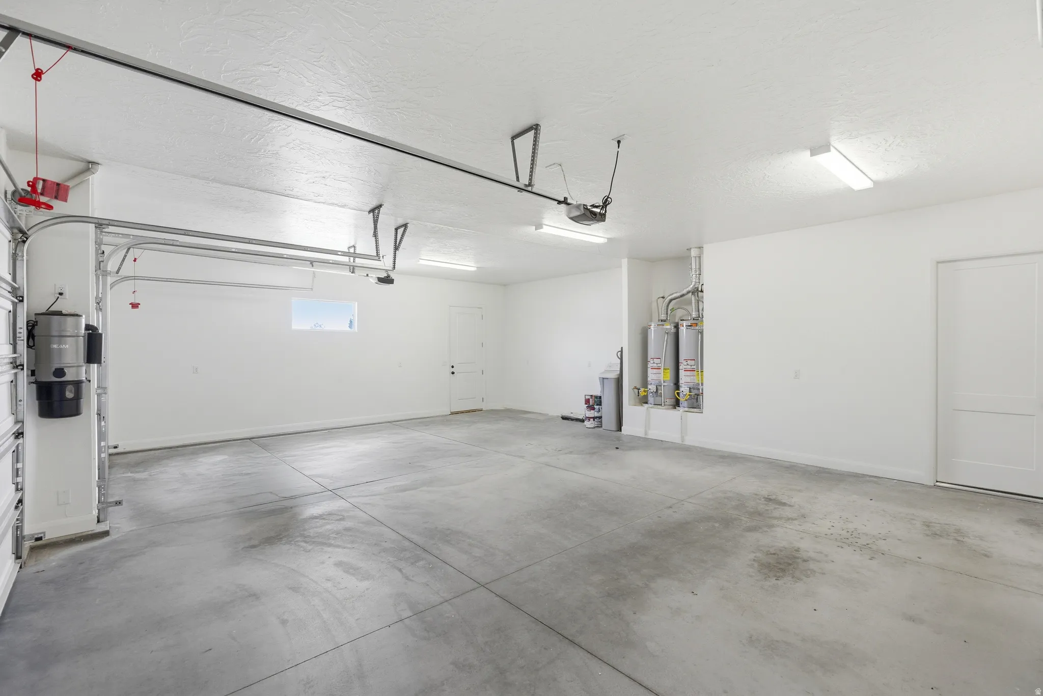 Garage featuring a central vacuum unit and gas water heater
