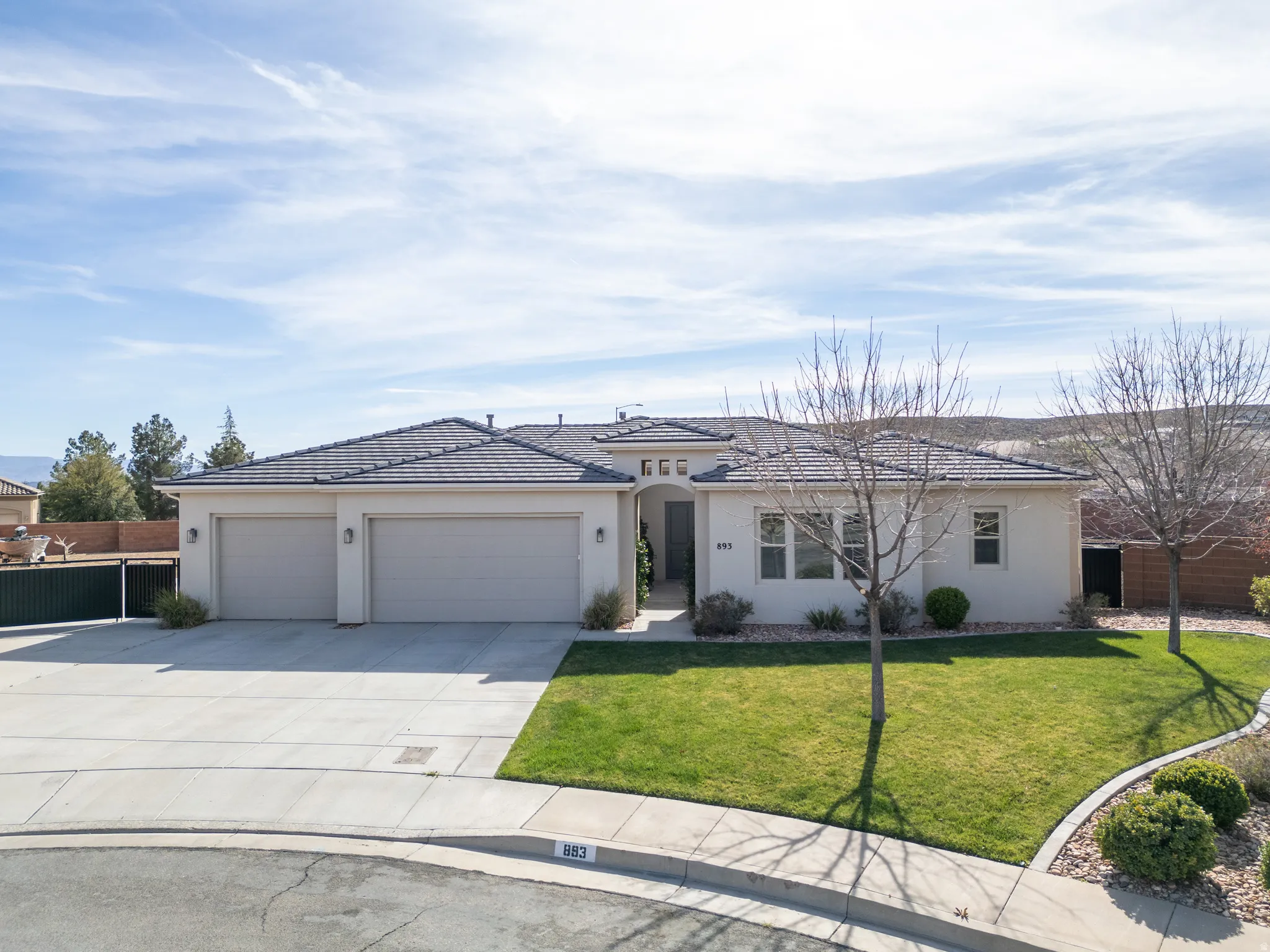 View of front of property featuring an attached garage, concrete driveway, and stucco siding