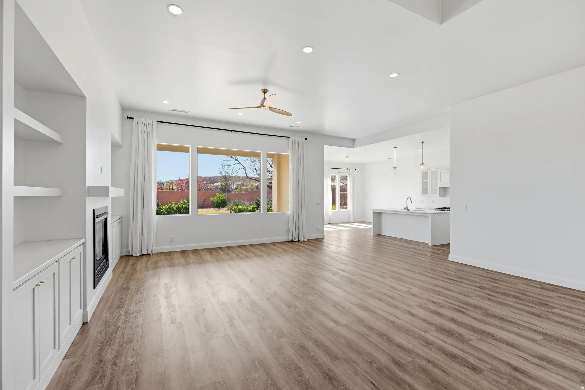 Unfurnished living room with ceiling fan, light wood-type flooring, recessed lighting, and a glass covered fireplace