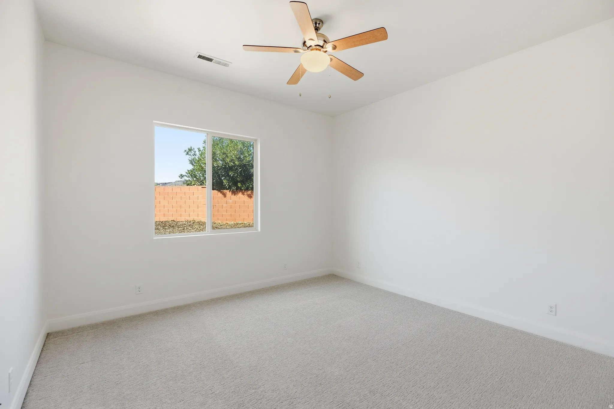Spare room featuring light colored carpet and a ceiling fan