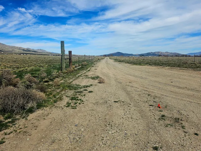 View of dirt / gravel road with a mountain view and a rural view