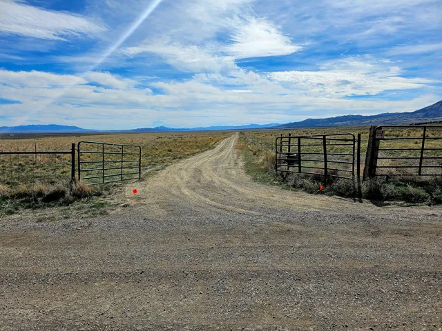 View of road with a gate, a mountain view, and a view of countryside