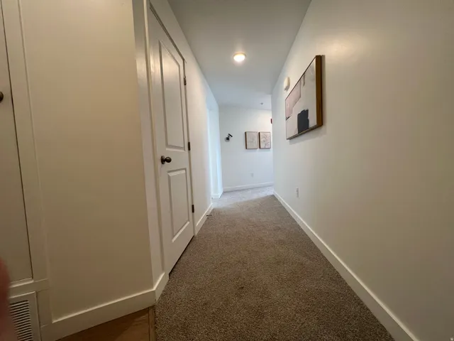 Corridor featuring baseboards and carpet