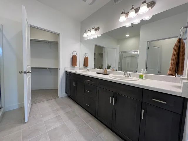 Bathroom featuring a stall shower, double vanity, and a spacious closet
