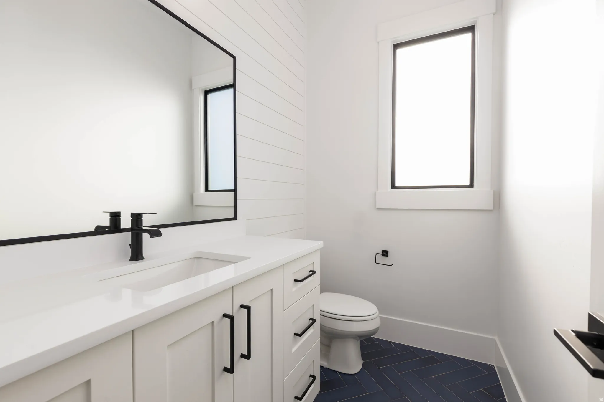 Half bath with vanity and dark tile patterned flooring