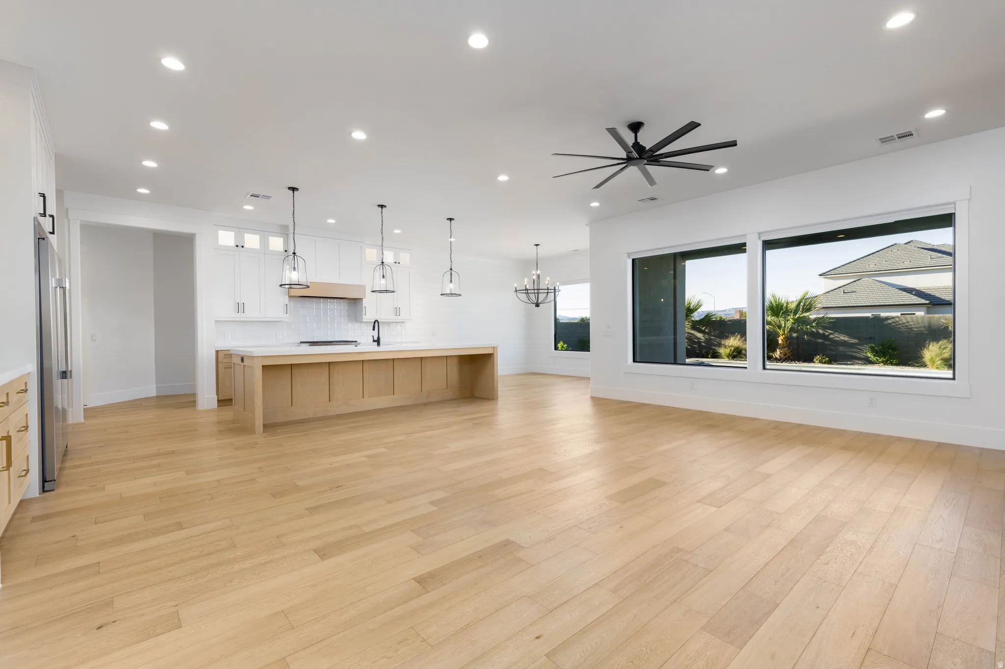 Kitchen featuring open floor plan, hanging lights, a large island, a ceiling fan, and light wood finished floors
