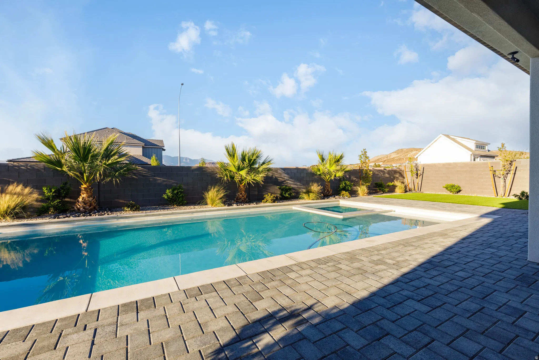 Integrated pool / hot tub with a fenced backyard and a patio area