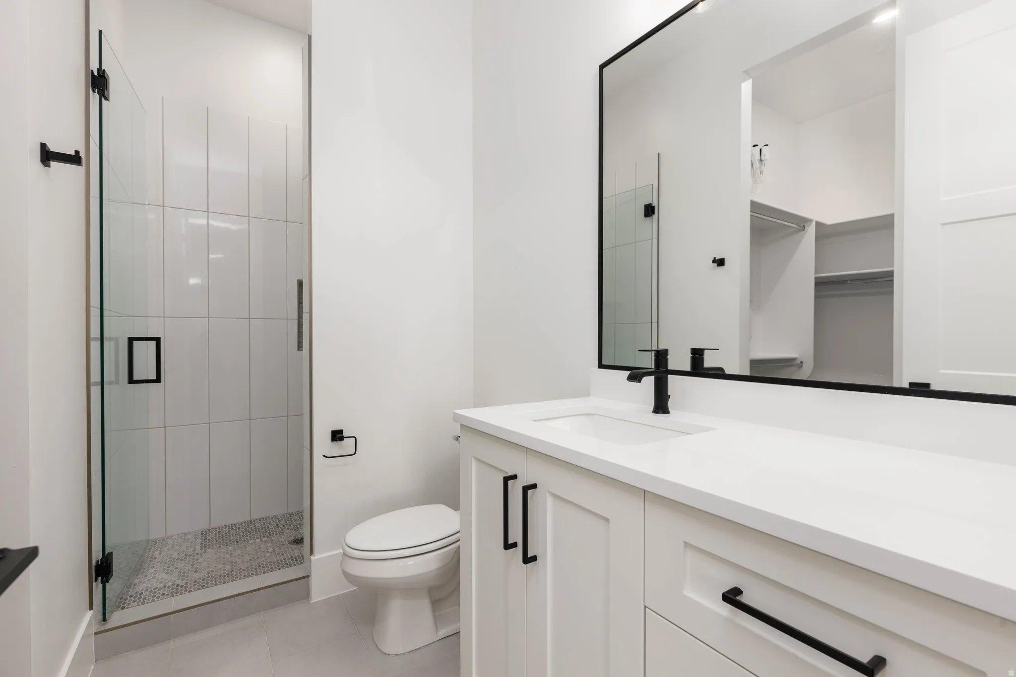 Full bath with vanity, a stall shower, light tile patterned flooring, and a walk in closet