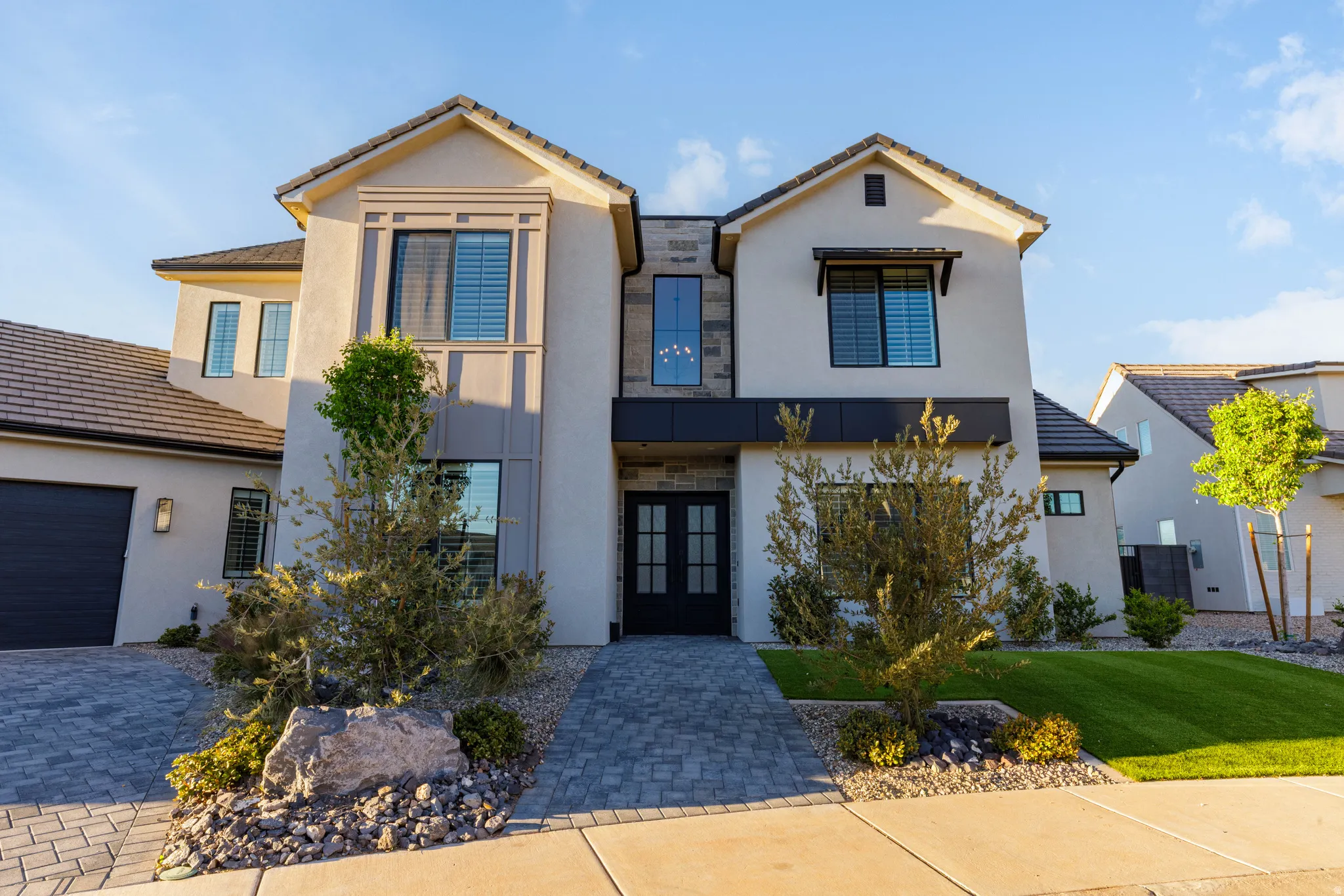 View of front facade with french doors, stucco siding, a front lawn, and driveway