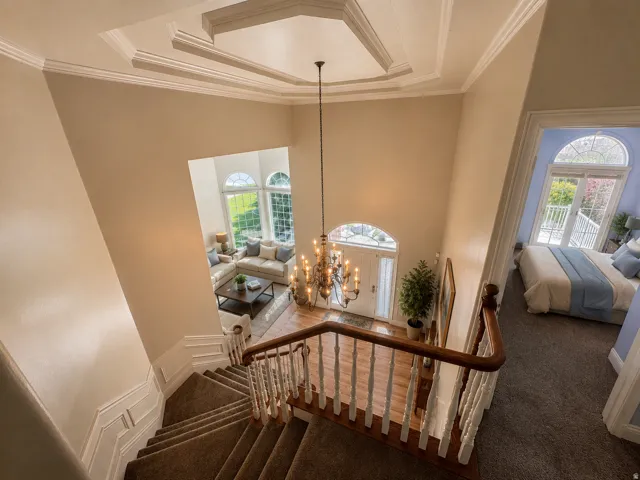 Grand foyer featuring a two-story ceiling with decorative trim, a chandelier, and wood-finish flooring AI-staged or enhanced