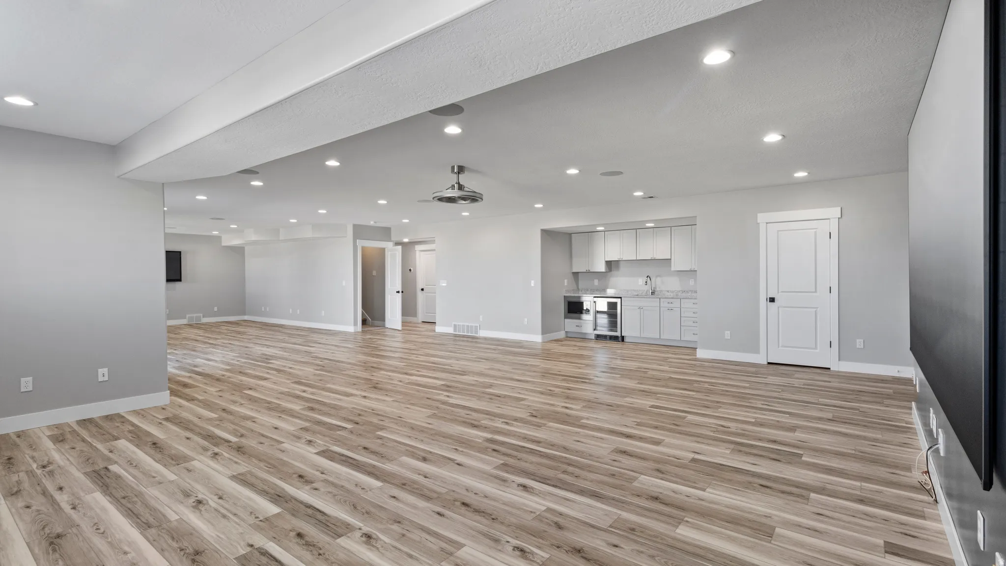 Unfurnished living room featuring light wood finished floors, recessed lighting, and beverage cooler