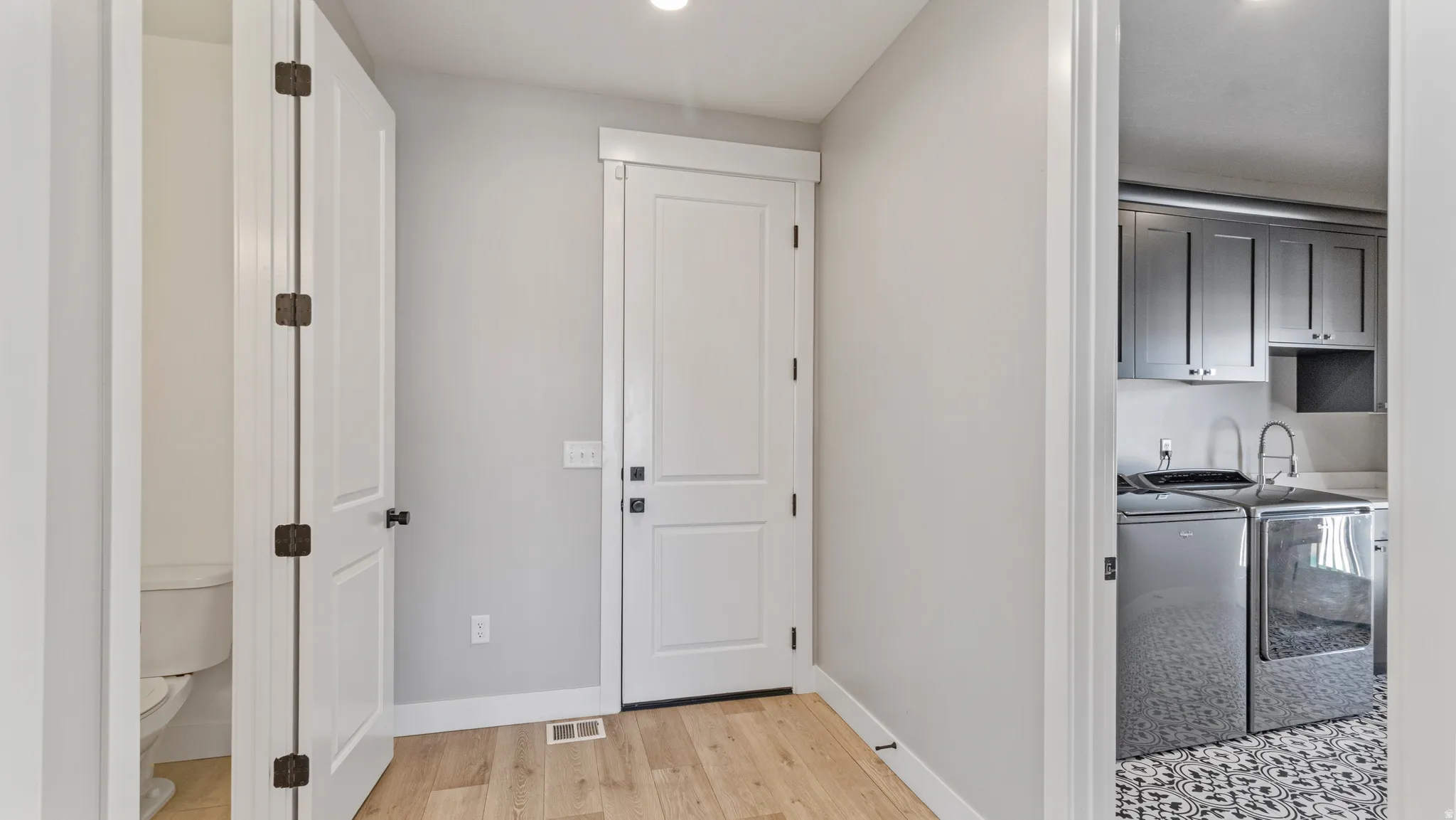 Laundry room with light wood finished floors, washing machine and clothes dryer, cabinet space, and recessed lighting