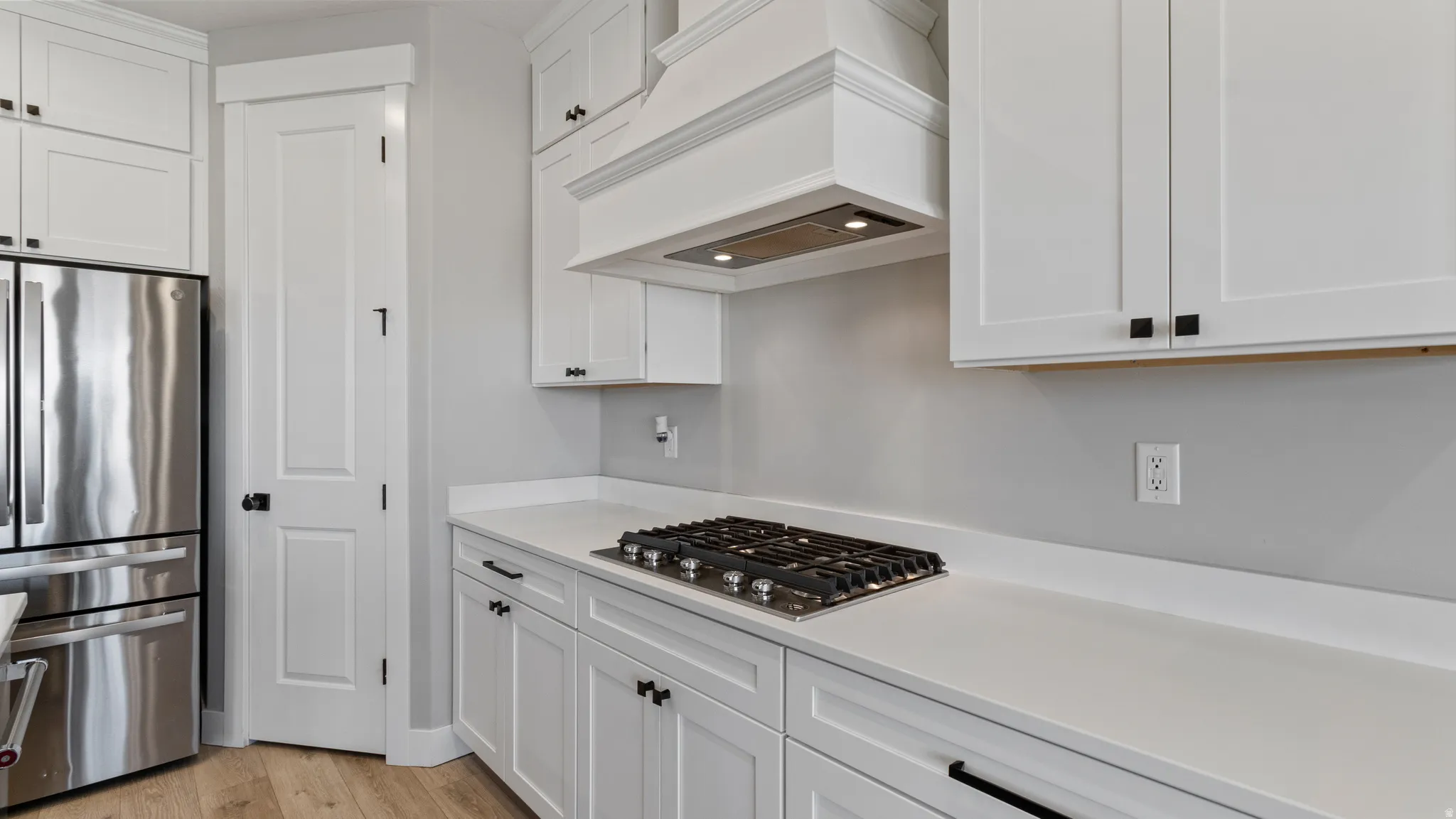 Kitchen with stainless steel appliances, white cabinetry, and light wood finished floors