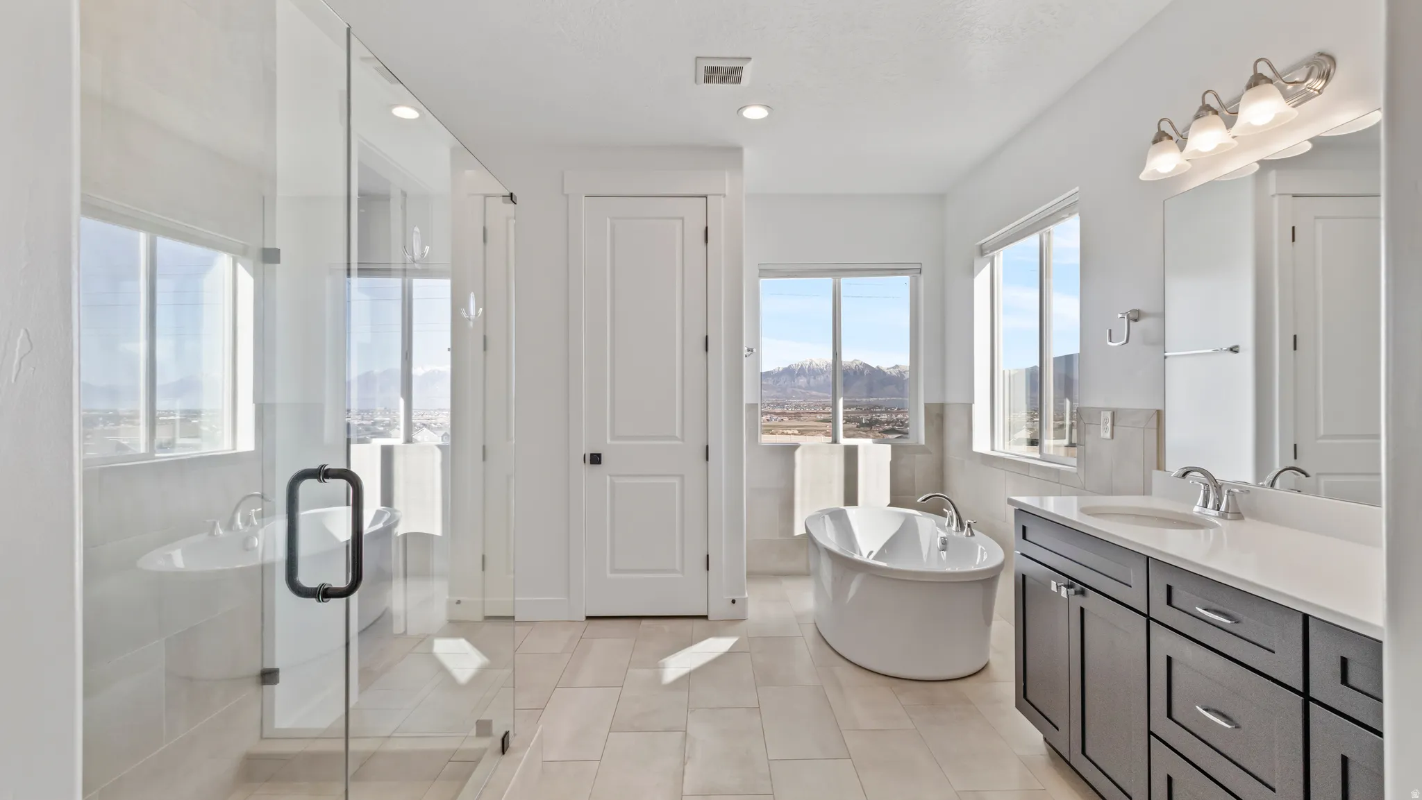 Full bath featuring a freestanding tub, vanity, a stall shower, tile walls, and a mountain view