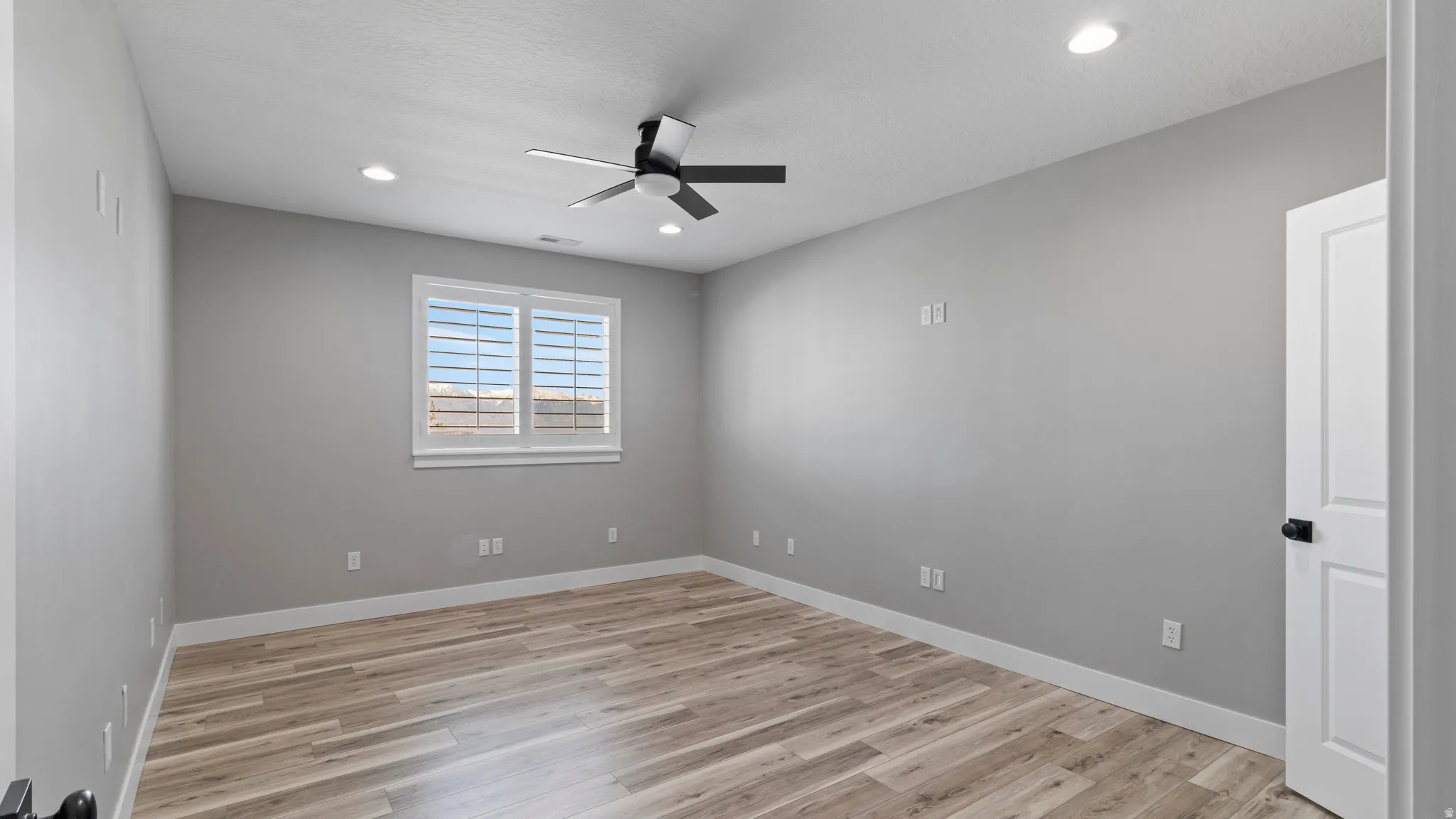 Empty room featuring light wood finished floors, ceiling fan, and recessed lighting