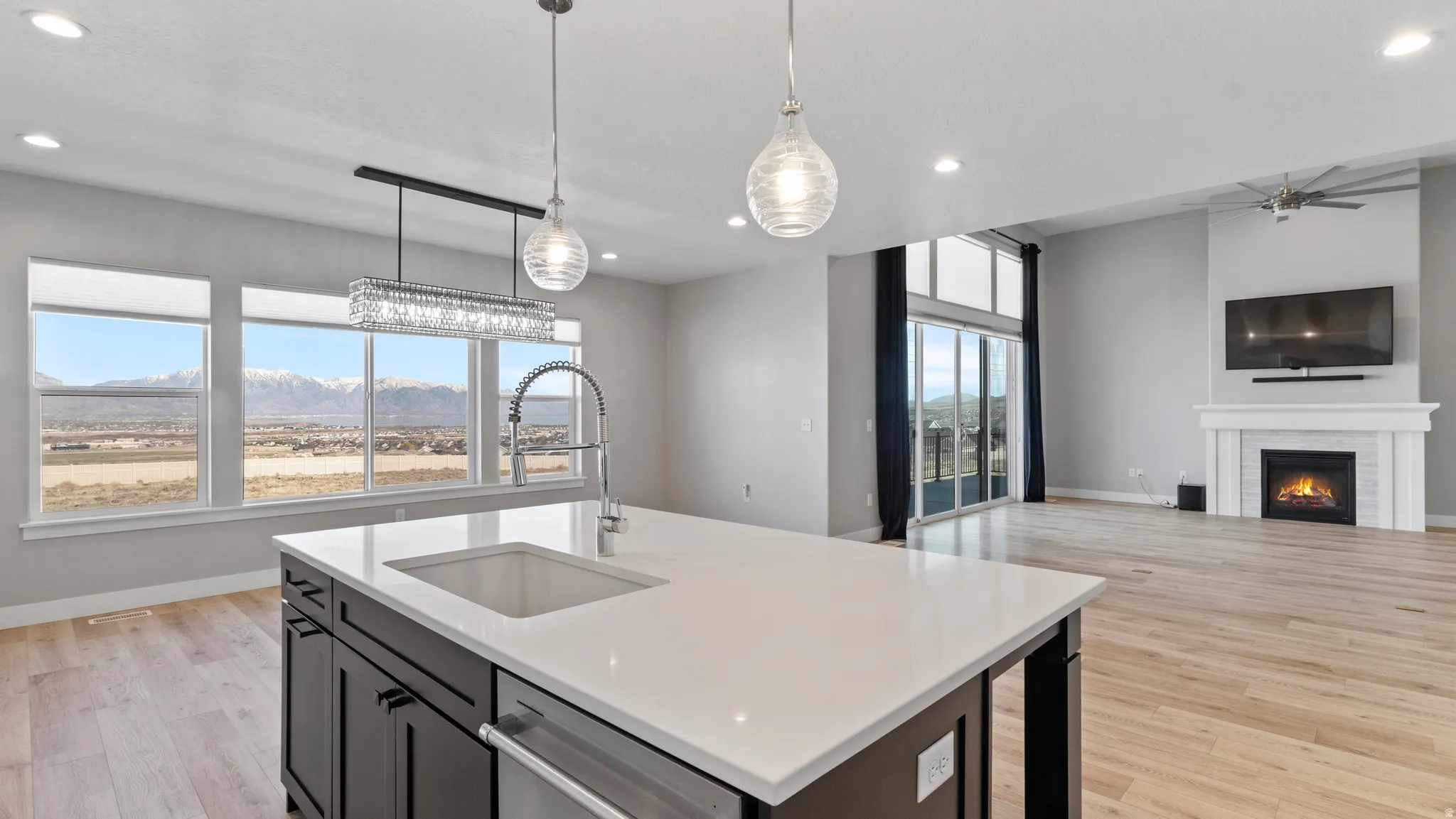 Kitchen with a mountain view, open floor plan, light wood-style floors, a lit fireplace, and a kitchen island with sink
