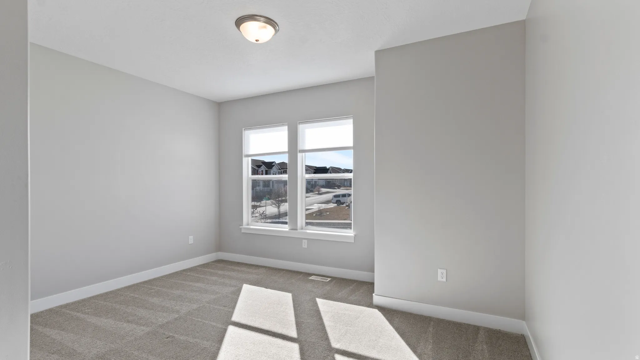 Spare room with light colored carpet and baseboards