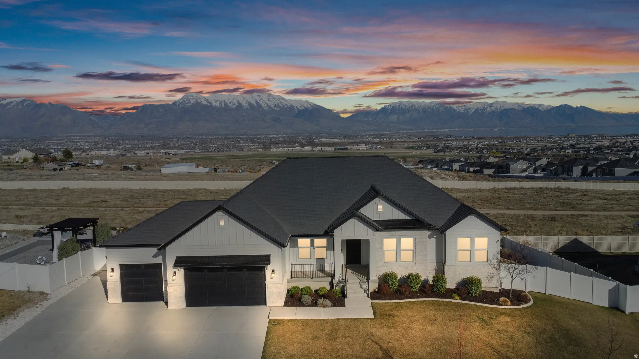Modern farmhouse featuring a mountain view, an attached garage, covered porch, driveway, and stone siding
