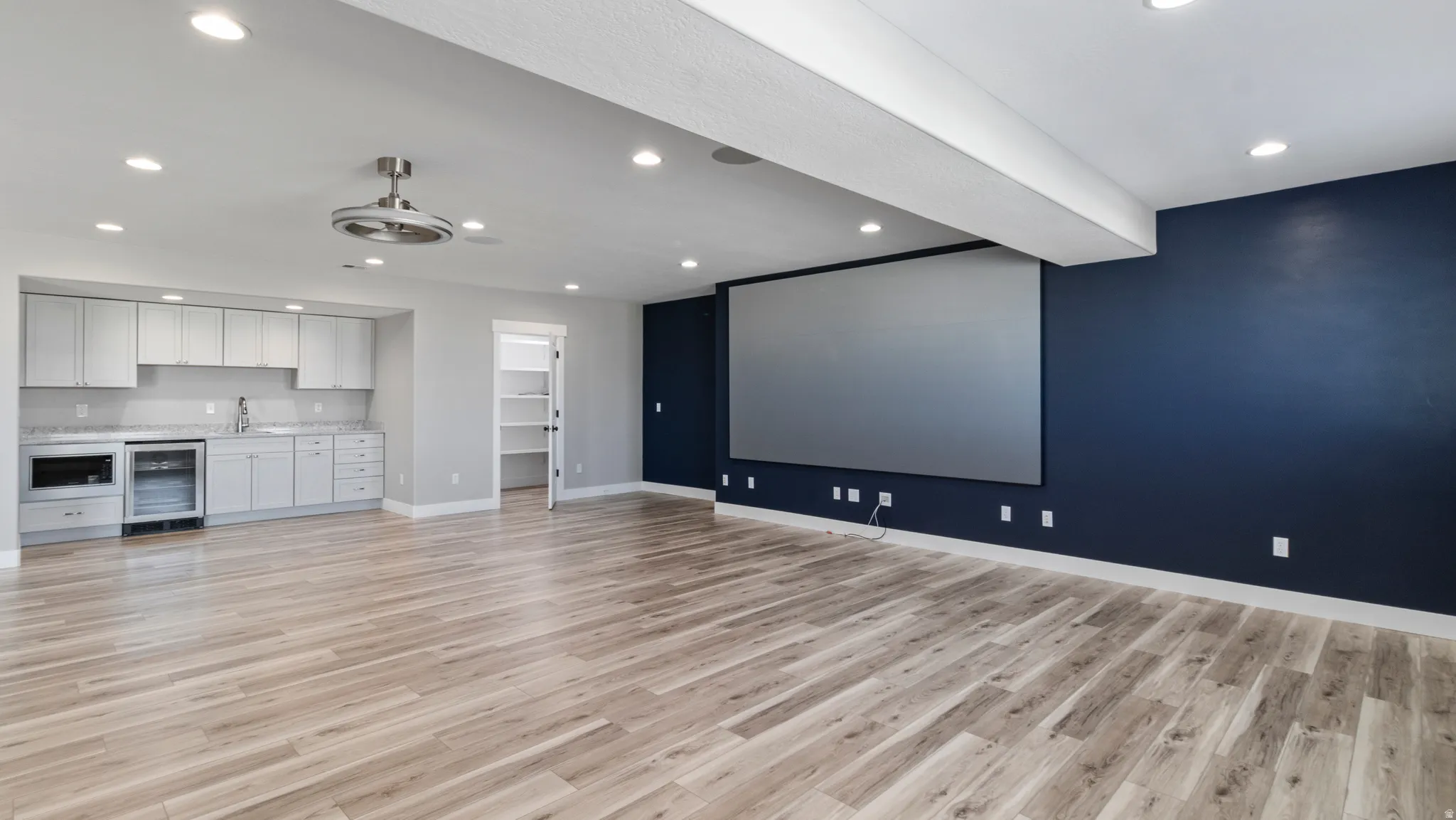 Cinema with wine cooler, recessed lighting, light wood-type flooring, and wet bar
