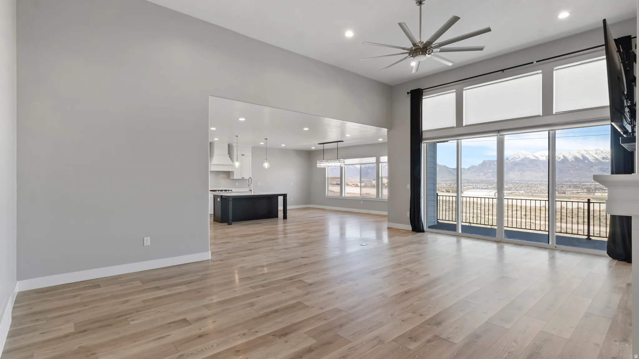 Unfurnished living room with recessed lighting, a ceiling fan, light wood-style flooring, and a high ceiling