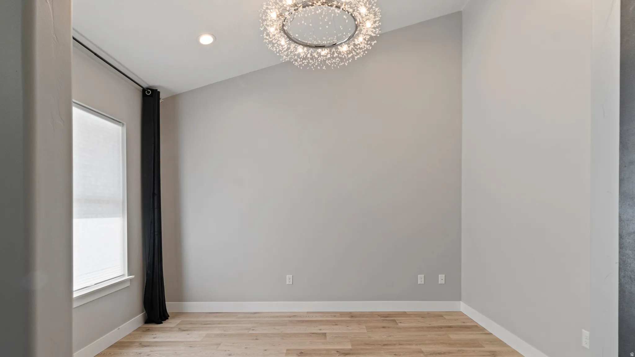Unfurnished room featuring suspended lighting and light wood-style flooring