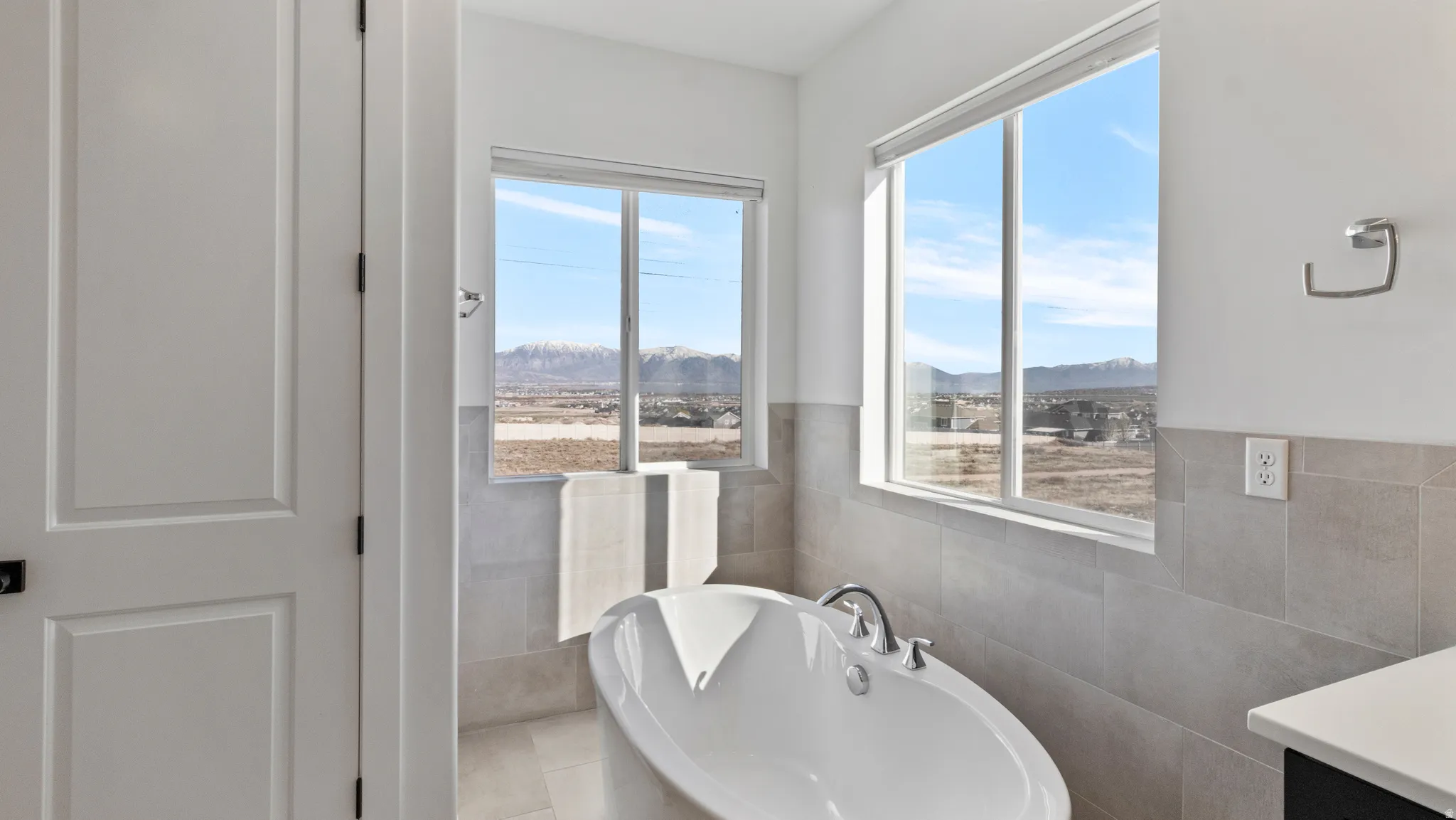 Full bathroom featuring a freestanding bath, a mountain view, and tile walls