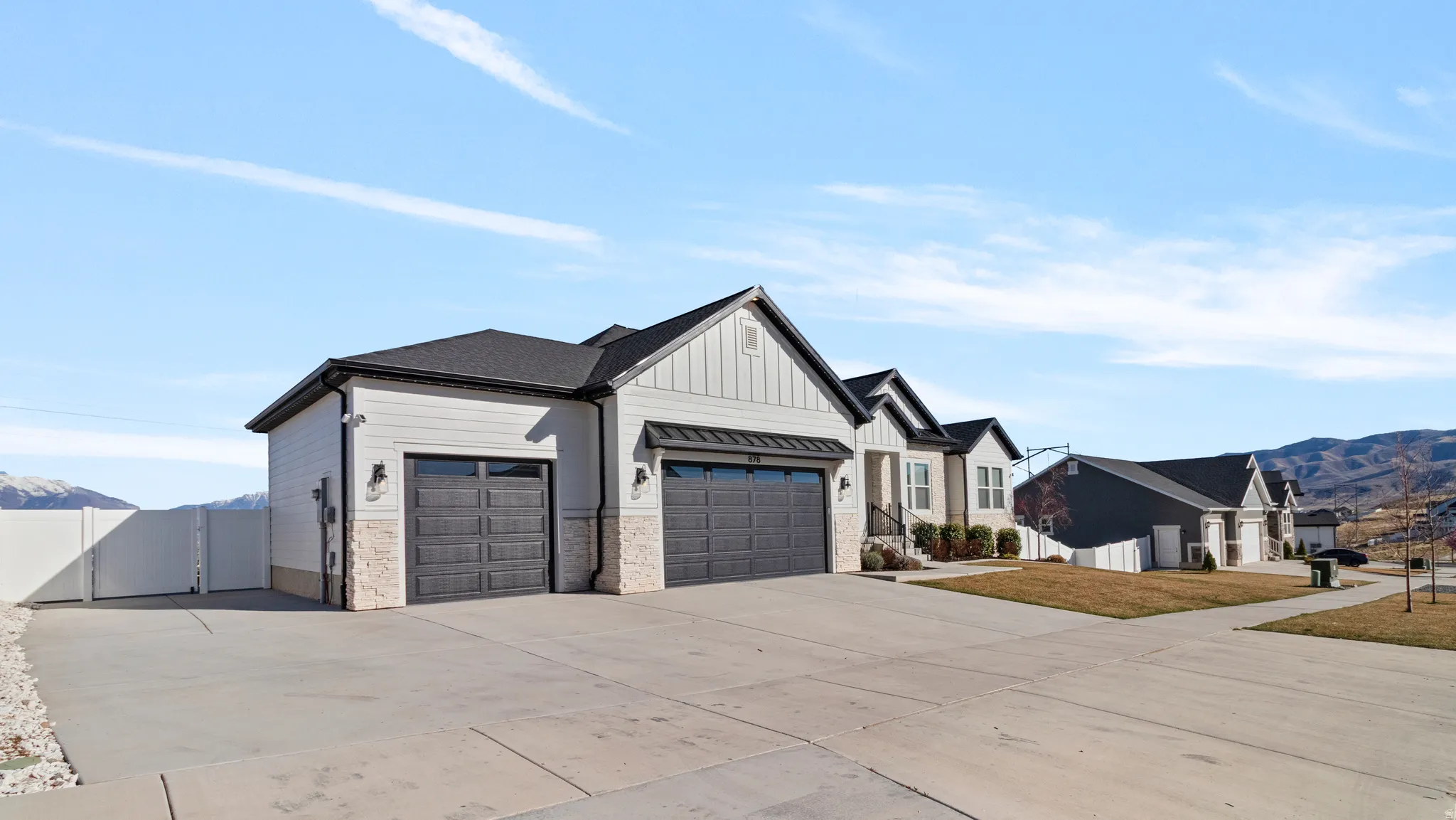 Modern farmhouse with a mountain view, a garage, driveway, board and batten siding, and a gate