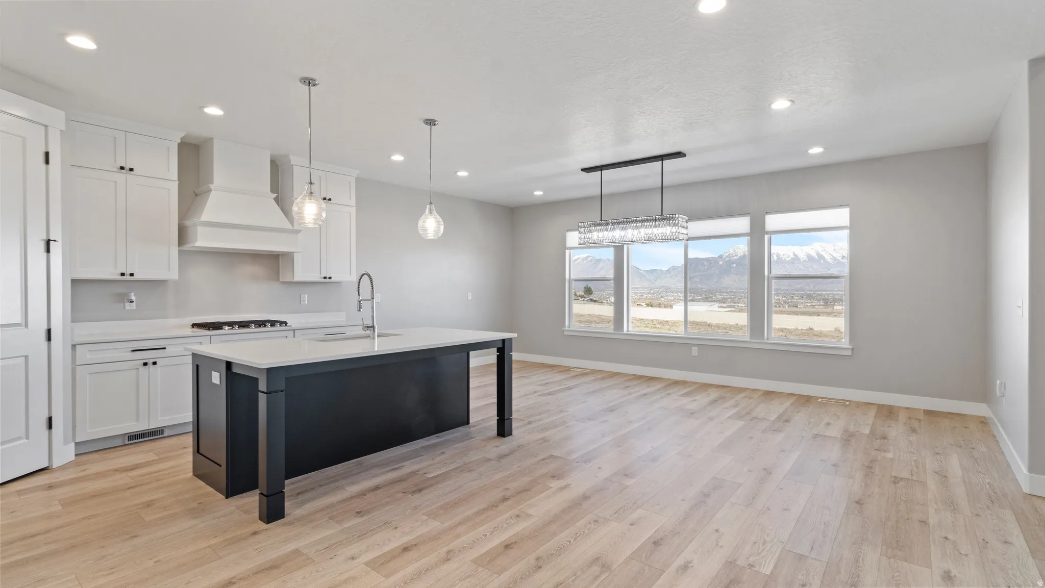 Kitchen featuring a mountain view, dual tone cabinets, a kitchen bar, an island with sink, and hanging light fixtures