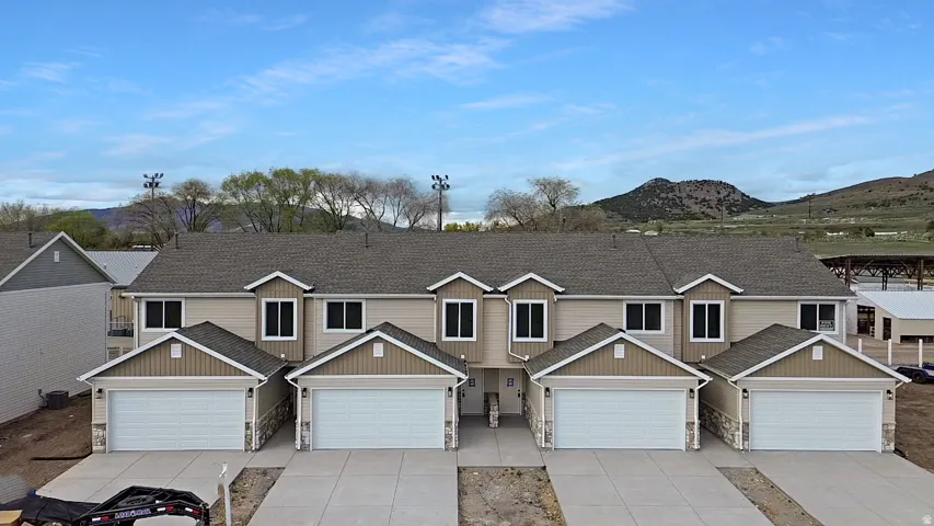 Craftsman inspired home featuring stone siding, roof with shingles, a mountain view, and driveway