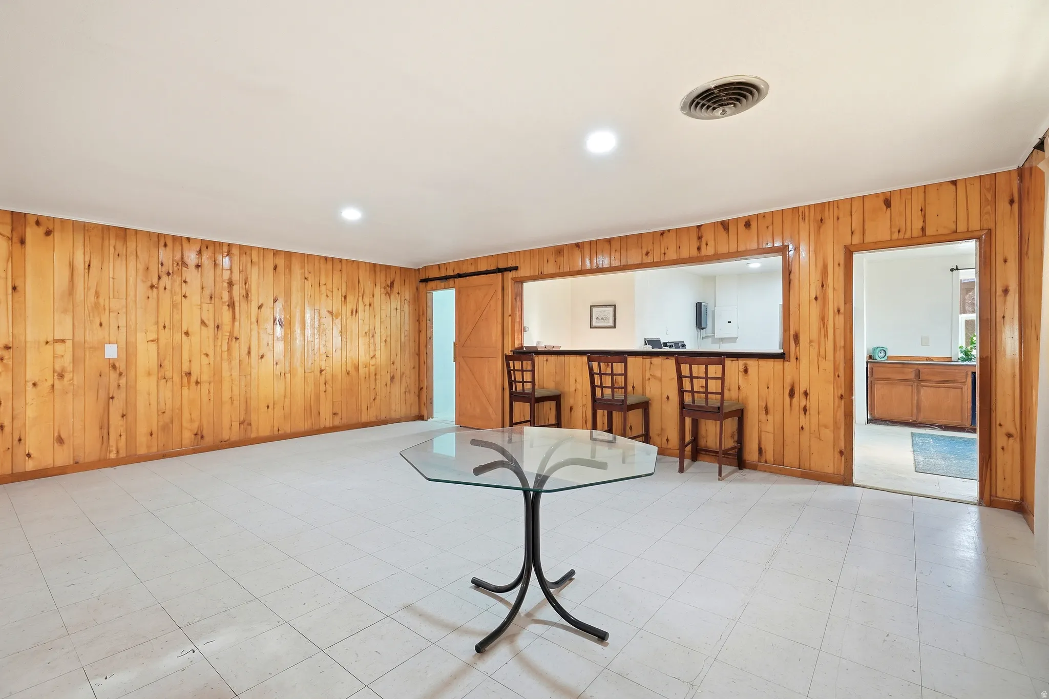 Unfurnished living room featuring wood walls, a barn door, tile patterned floors, and recessed lighting