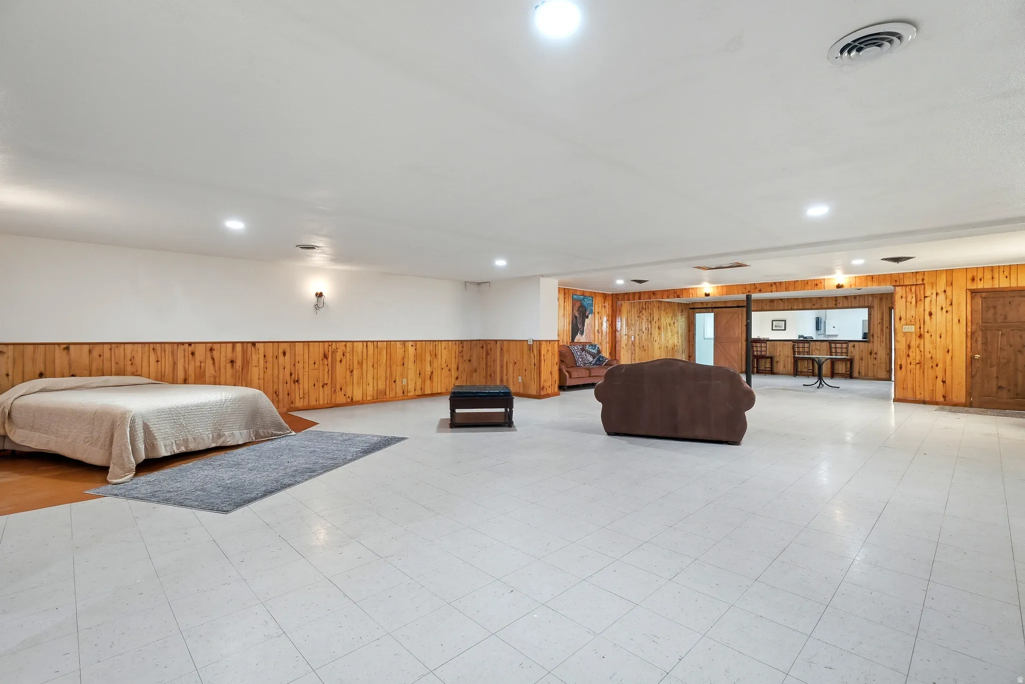 Bedroom with wooden walls, light flooring, a wainscoted wall, and recessed lighting
