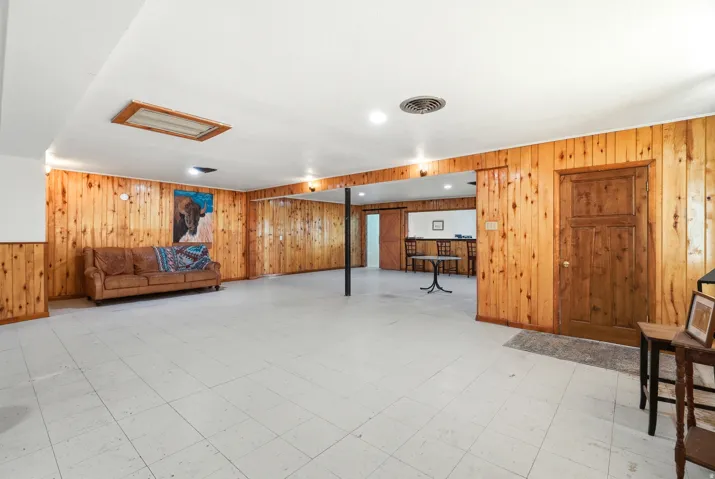 Finished below grade area with light flooring, wood walls, and recessed lighting