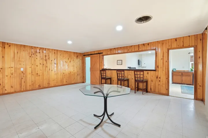 Unfurnished living room featuring wood walls, a barn door, tile patterned floors, and recessed lighting
