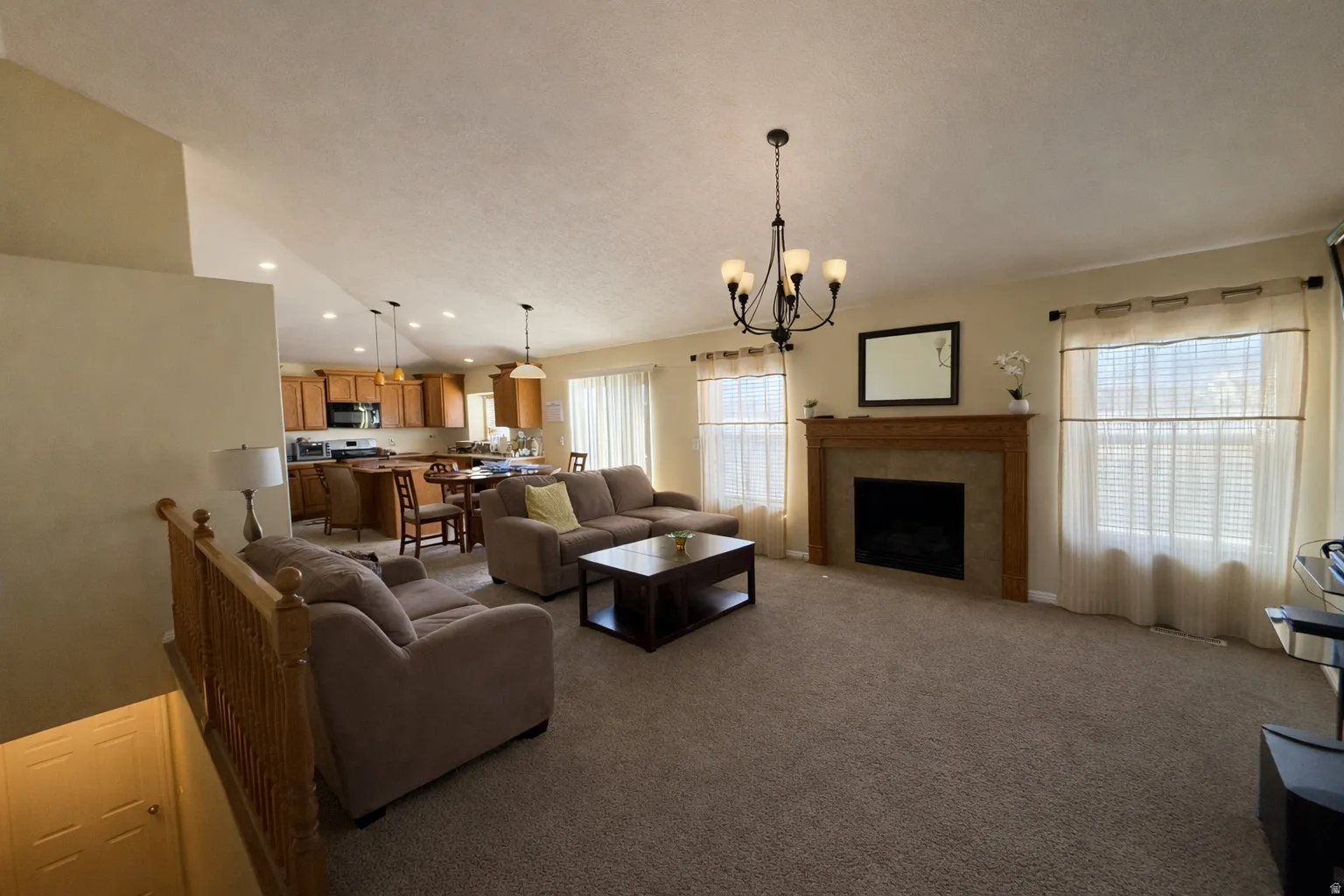 Living area with carpet floors, a tiled fireplace, and a chandelier