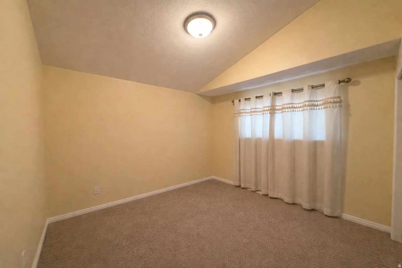 Empty room featuring lofted ceiling and carpet floors