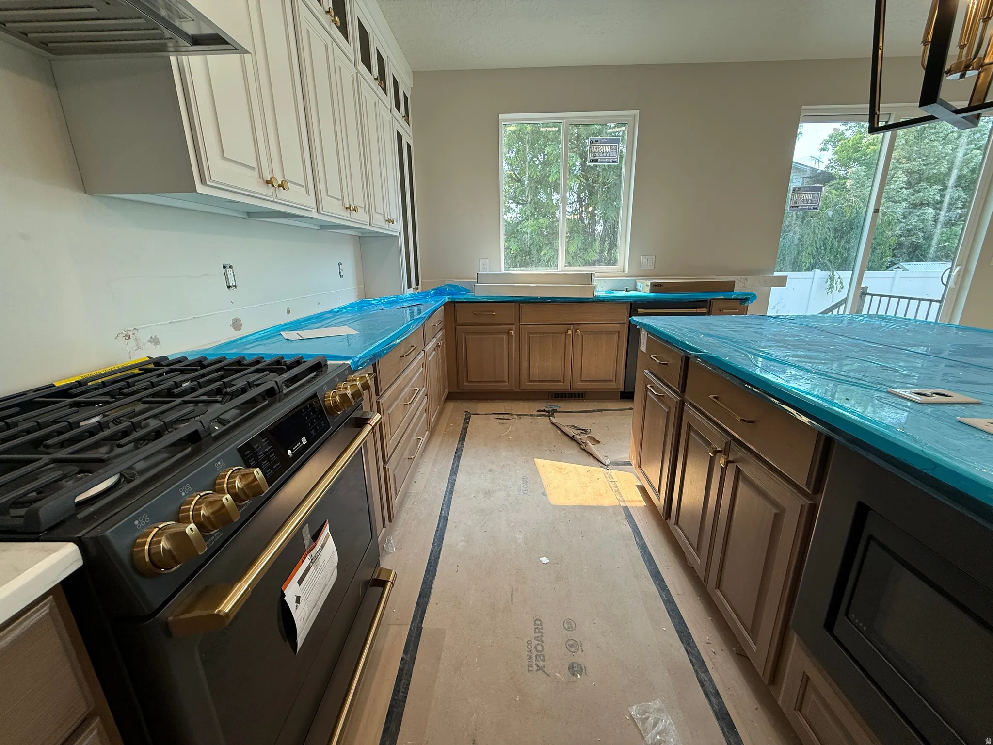 Modern kitchen featuring a built-in range, stainless steel range hood, two-tone cabinetry, a central island, and multiple windows