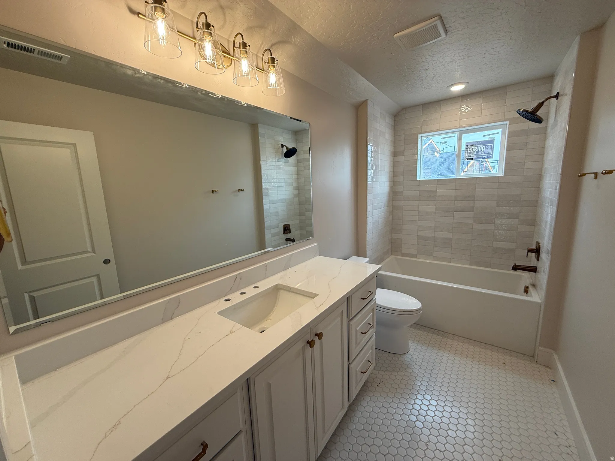 Bathroom featuring a white vanity with a quartz countertop, an undermount sink, and brass hardware