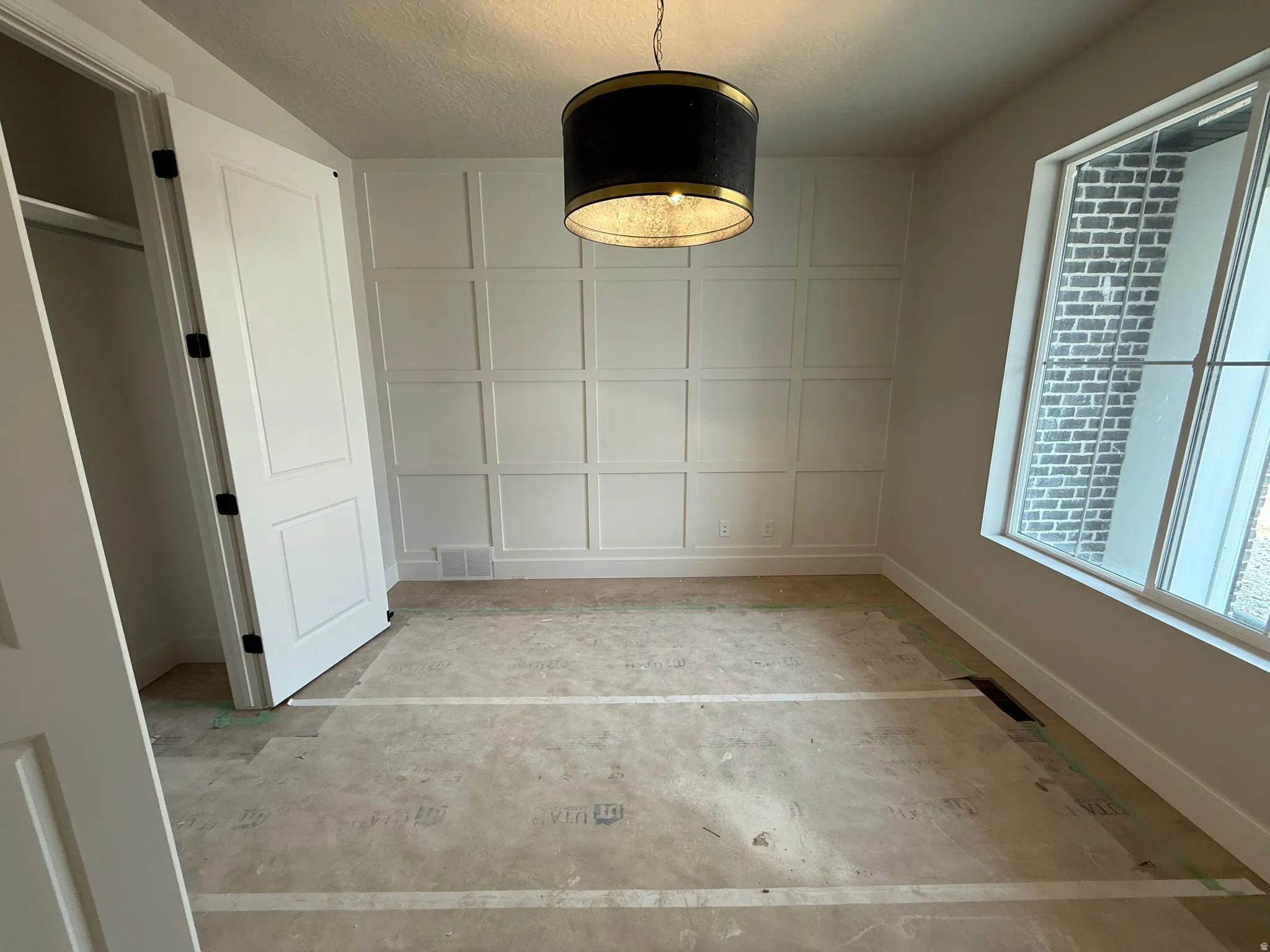 Room featuring a decorative wainscoting accent wall and a drum pendant light fixture