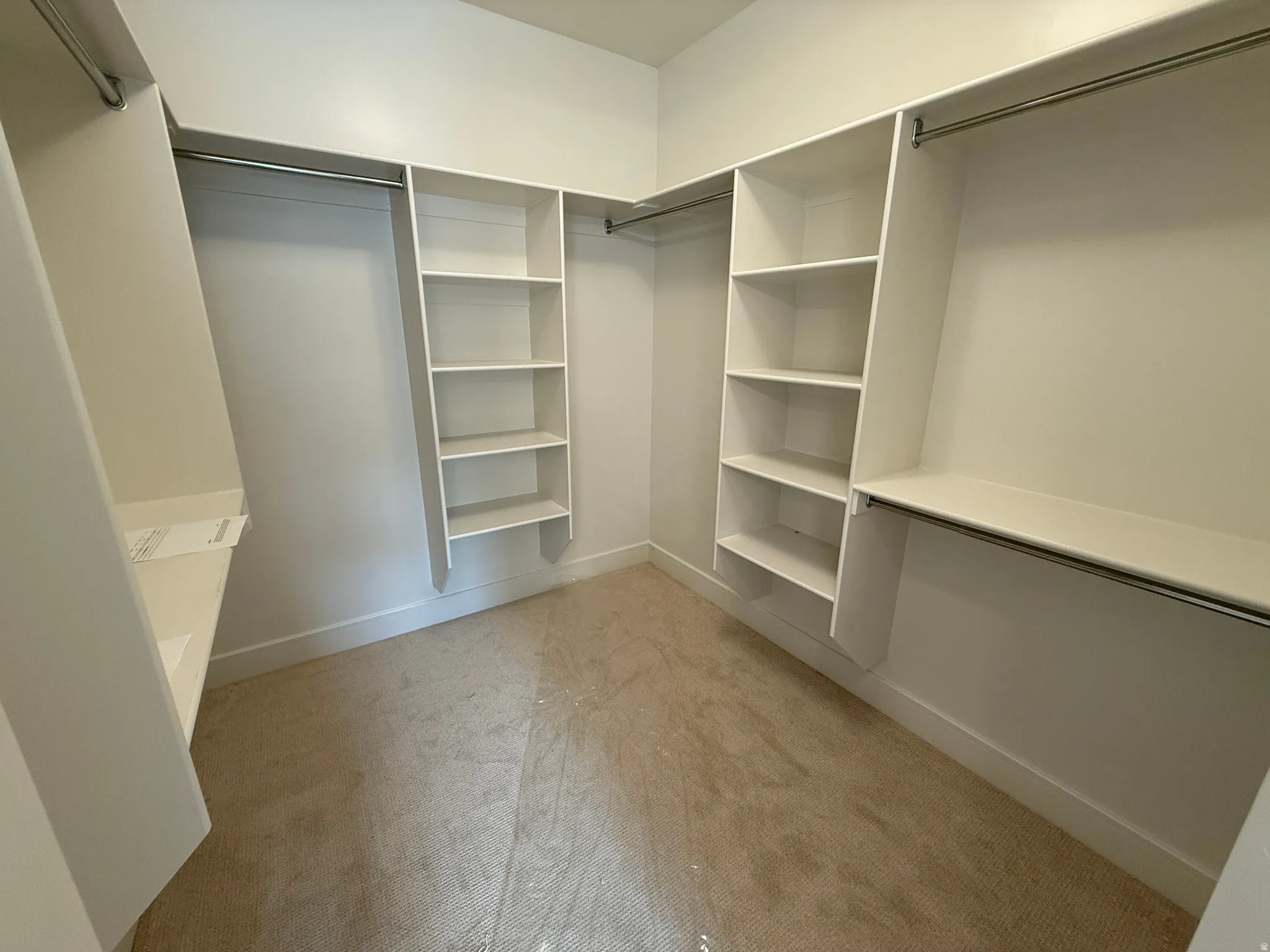 Walk-in closet featuring built-in shelving, multiple hanging rods, and neutral-toned carpeting