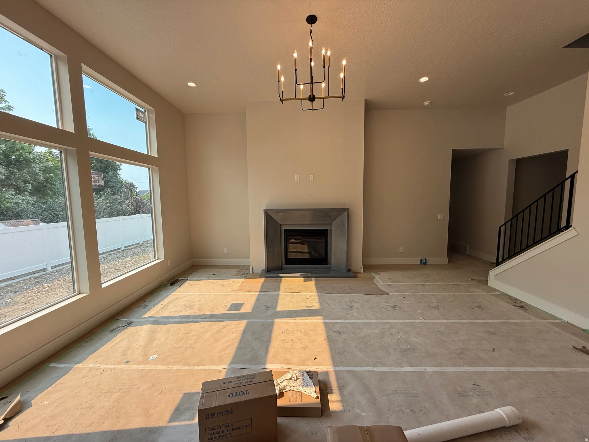 Spacious living area featuring large picture windows, a modern fireplace with a stone surround, and an elegant chandelier