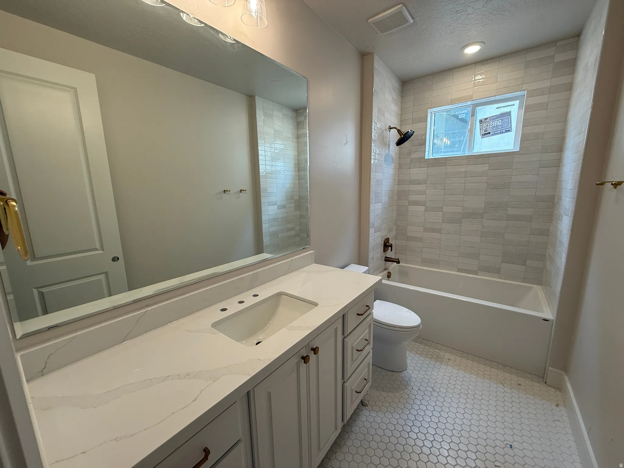 Bathroom featuring a white vanity with an integrated sink, a large wall-mounted mirror, and a tiled shower/tub combination