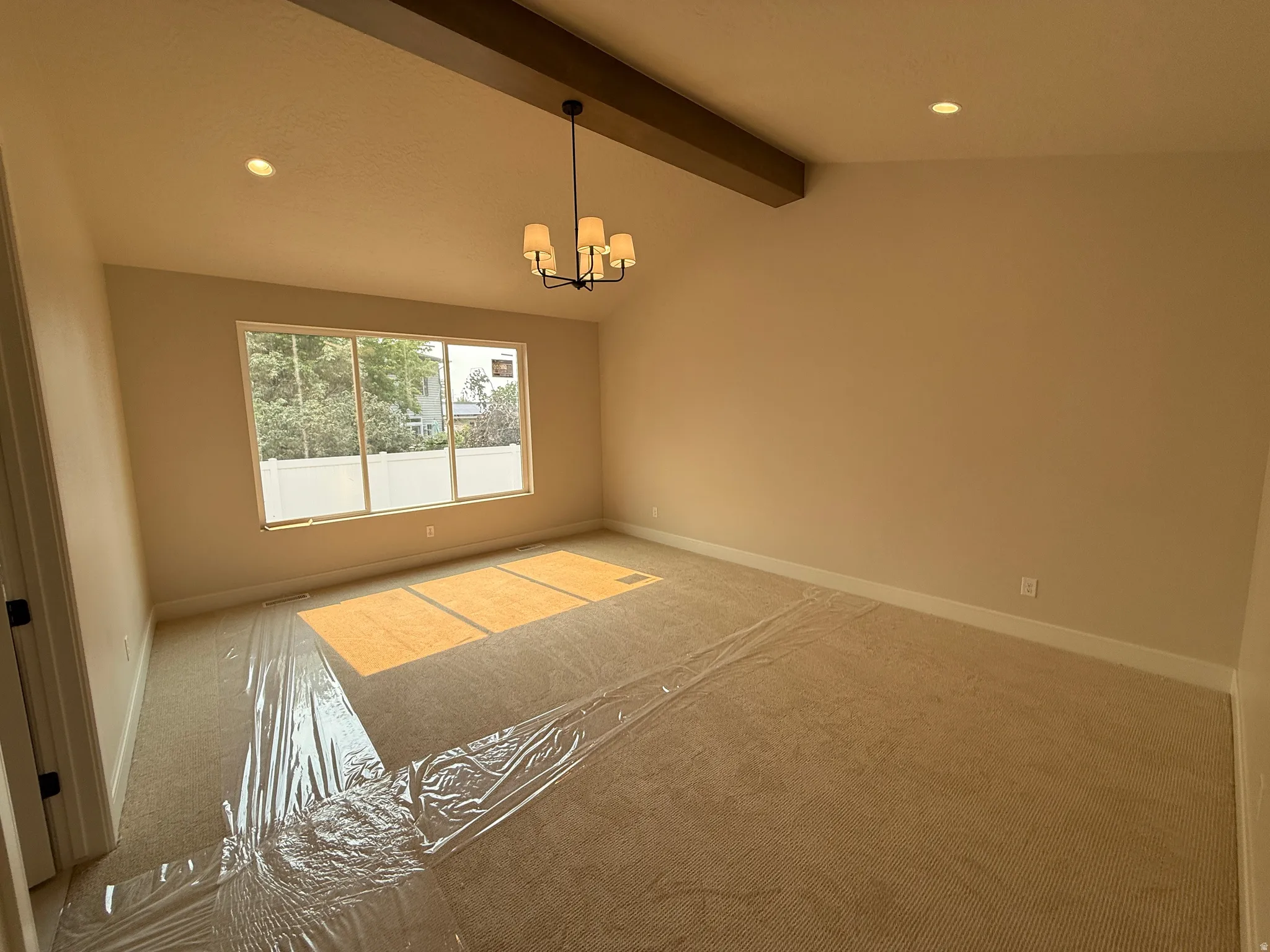 Primary Bedroom featuring a vaulted ceiling with a decorative wood beam and a contemporary chandelier